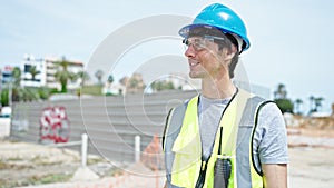 Young hispanic man architect smiling confident wearing hardhat at construction place