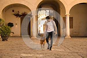 Young Hispanic man with beard and sunglasses walking with his dog very happy. Concept animals, dogs, love, pets, golden