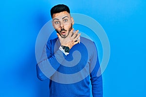 Young hispanic man with beard wearing casual blue sweater looking fascinated with disbelief, surprise and amazed expression with
