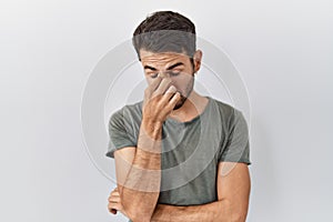 Young hispanic man with beard wearing casual t shirt over white background tired rubbing nose and eyes feeling fatigue and