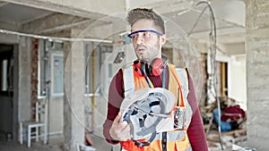 Young hispanic man builder tired using hardhat as a hand fan at construction site
