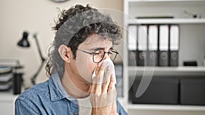 Young hispanic man business worker being sick using napkin at office