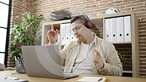 Young hispanic man business worker dancing using laptop at office