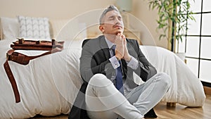 Young hispanic man business worker praying sitting on floor at hotel room