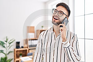 Young hispanic man business worker smiling confident talking on smartphone at office