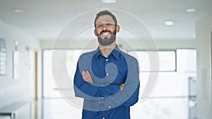 Young hispanic man business worker standing with arms crossed gesture at the office