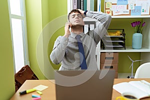 Young hispanic man business worker stressed talking on smartphone at office