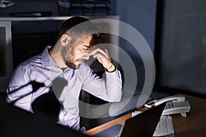 Young hispanic man business worker stressed working overtime at office