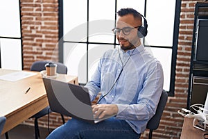 Young hispanic man business worker using laptop and headphones at office