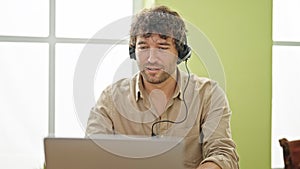 Young hispanic man business worker using laptop and headphones at office