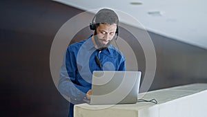Young hispanic man business worker using laptop and headphones smiling at the office
