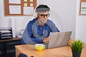 Young hispanic man business worker using laptop and headphones working at office