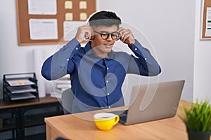 Young hispanic man business worker using laptop and headphones working at office