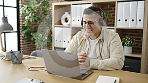 Young hispanic man business worker using laptop wearing headphones at office