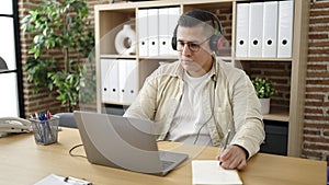 Young hispanic man business worker using laptop wearing headphones at office