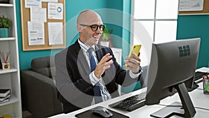 Young hispanic man business worker worming having video call on smartphone at the office