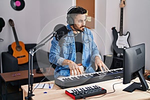 Young hispanic man composer composing song at music studio