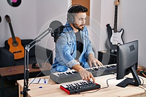 Young hispanic man composer composing song at music studio