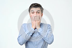 Young hispanic man covering his mouth with hand