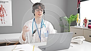 Young hispanic man doctor doing video call with laptop at clinic