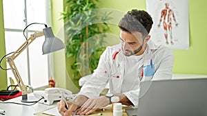 Young hispanic man doctor prescribe pills writing medical report at clinic