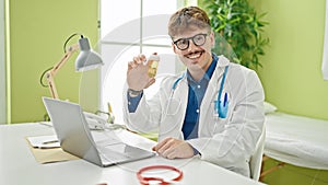 Young hispanic man doctor prescribing pills smiling at the clinic