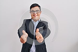 Young hispanic man with down syndrome wearing business style approving doing positive gesture with hand, thumbs up smiling and