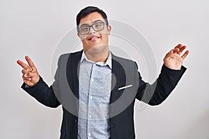 Young hispanic man with down syndrome wearing business style showing and pointing up with fingers number seven while smiling