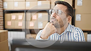 Young hispanic man ecommerce business worker sitting on table thinking at office