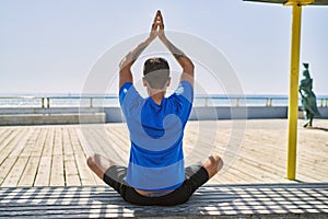 Young hispanic man exercising doing tree pose outdoors