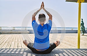 Young hispanic man exercising doing tree pose outdoors