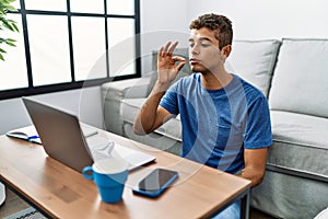 Young hispanic man gesturing sign language on video call at home