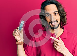 Young hispanic man holding computer memory smiling happy pointing with hand and finger