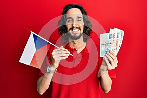 Young hispanic man holding czech republic flag and koruna banknotes smiling with a happy and cool smile on face