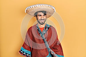 Young hispanic man holding mexican hat looking away to side with smile on face, natural expression