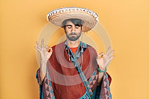 Young hispanic man holding mexican hat relax and smiling with eyes closed doing meditation gesture with fingers