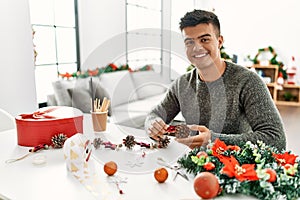 Young hispanic man make handsmade christmas decoration at home