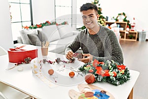 Young hispanic man make handsmade christmas decoration at home