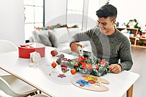 Young hispanic man make handsmade christmas decoration at home