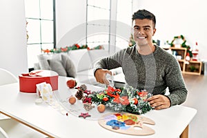 Young hispanic man make handsmade christmas decoration at home