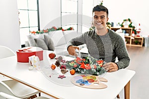 Young hispanic man make handsmade christmas decoration at home