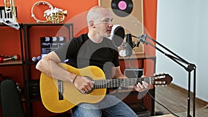 Young hispanic man musician singing song playing classical guitar at music studio