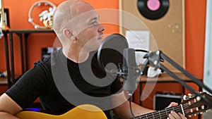 Young hispanic man musician singing song playing classical guitar at music studio