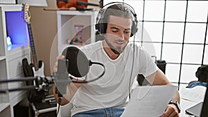 Young hispanic man musician singing song smiling at radio studio