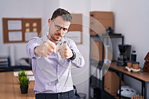 Young hispanic man at the office punching fist to fight, aggressive and angry attack, threat and violence