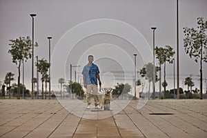 Young Hispanic man, posing with his dog in the middle of a lonely street in the early morning. Concept, dogs, pets, animals,