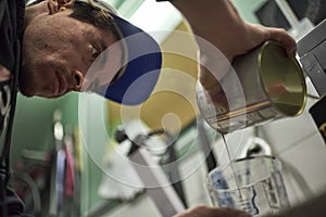 Young hispanic man pouring paint for painting a bicycle in his workshop