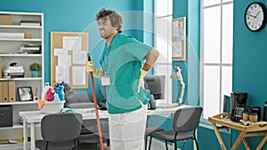 Young hispanic man professional cleaner cleaning floor suffering for backache at office