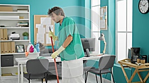 Young hispanic man professional cleaner cleaning floor suffering for backache at office