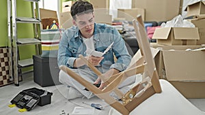 Young hispanic man reading instructions to repair chair at new home